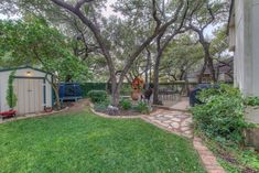 a backyard with trees, grass and a shed in the middle of it's yard