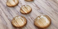 several wooden buttons are arranged on a wood surface with drops of water in the middle