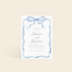 a wedding card with a blue ribbon and bow on the front, in watercolor