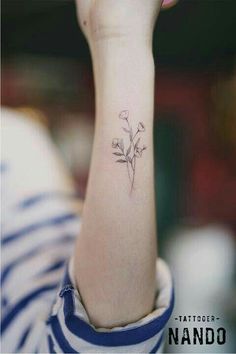 a small flower tattoo on the left inner forearm and wrist is shown in black ink