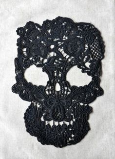 a black crocheted sugar skull with flowers on it's face is shown