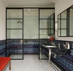 a bathroom with blue tiles and mirrors on the wall, two sinks and a bench