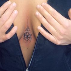 a close up of a person holding their hands on her chest with a flower tattoo