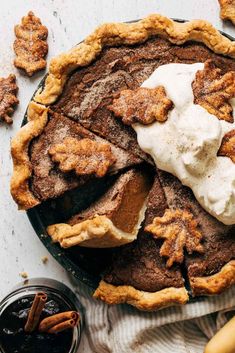 an apple pie with whipped cream on top and cinnamon sticks in the foreground next to it