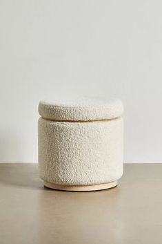 a white round box sitting on top of a table next to a wall and floor