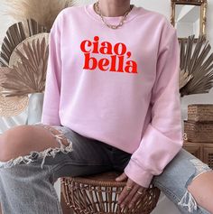 "Ciao, Bella Sweatshirt. A flirty saying in Italian that means \"Hello, Beautiful\". A sturdy and warm sweatshirt bound to keep you warm in the colder months. A pre-shrunk, classic fit sweater that's made with air-jet spun yarn for a soft feel and reduced pilling. * 50% cotton, 50% polyester * Pre-shrunk * Classic fit * 1x1 athletic rib knit collar with spandex * Air-jet spun yarn with a soft feel and reduced pilling * Double-needle stitched collar, shoulders, armholes, cuffs, and hem This product is made especially for you as soon as you place an order, which is why it takes us a bit longer to deliver it to you. Making products on demand instead of in bulk helps reduce overproduction, so thank you for making thoughtful purchasing decisions!" Cute Sweater With Letter Print And Relaxed Fit, Cute Crew Neck Sweater With Letter Print, Cute Relaxed Fit Sweater With Letter Print, Cute Relaxed Fit Sweatshirt With Letter Print, Cute Crew Neck Sweatshirt With Slogan, Cute Long Sleeve Tops With Funny Text, Cute Slogan Crew Neck Sweatshirt, Pink Cotton Sweater With Slogan, Cute Slogan Sweatshirt Relaxed Fit