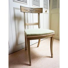 a wooden chair sitting in front of a white wall with shutters on the doors