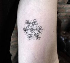 a small black and white snowflake tattoo on the right arm, with leaves