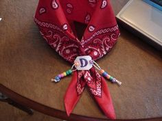 a red bandana sitting on top of a wooden table next to a laptop computer