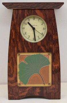 a wooden clock with a green leaf on it