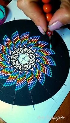 a person is painting on a piece of paper with colored circles and dots in the center