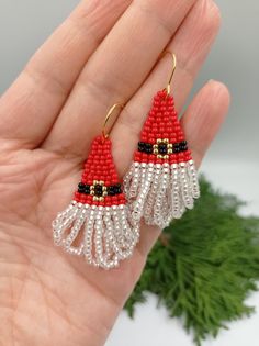 a pair of red and white beaded earrings with santa hats on it's ears