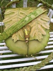 a large green object sitting on top of a white bench next to some grass and plants