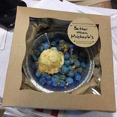 a box filled with blueberries and ice cream on top of a table next to a cell phone