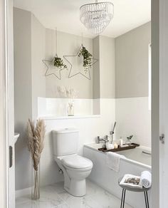 a bathroom with a white toilet sitting next to a bath tub under a chandelier