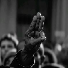 a black and white photo of a person holding their hand up in the air with both hands raised