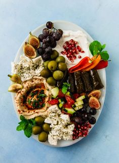 a white plate topped with olives, bread and other foods on top of a blue table