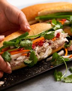 two sandwiches with meat, lettuce and carrots are on a black plate