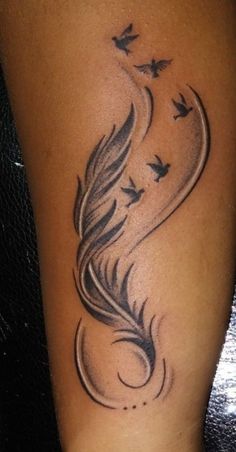 a woman's leg with a tattoo on it that has birds flying in the sky