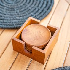 a wooden box sitting on top of a wooden floor next to a rug and bowl