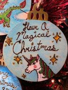 some christmas ornaments are hanging from a tree with decorations around them and the words have a magic christmas written on one ornament