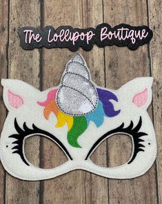 a close up of a mask on a wooden surface with the words the lollipop boutique