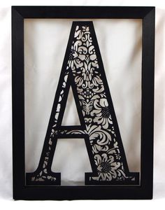 the letter a is cut out of paper and placed in a black frame on a white background