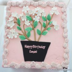 a pink birthday cake with white flowers in a black vase on the top and happy birthday any name here