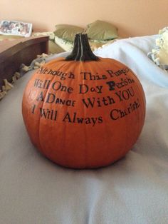 a pumpkin with writing on it sitting on a bed