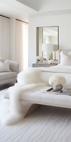 a bedroom with white furniture and large mirror on the wall above it's bed