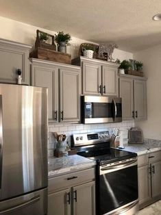 a kitchen with stainless steel appliances and granite counter tops, along with potted plants on top of the cabinets