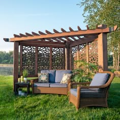 an outdoor living area with couches, table and pergolated trellis on the grass