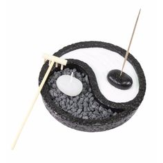 a black and white yin - yang incense bowl with two sticks sticking out of it