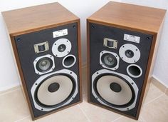 two speakers sitting next to each other on top of a tile floor in front of a white wall