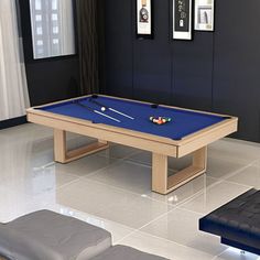 a pool table in the middle of a room with two couches and pictures on the wall