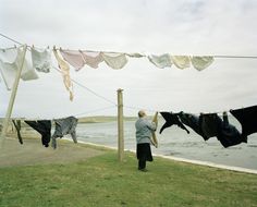 a woman hanging out clothes on a line by the water