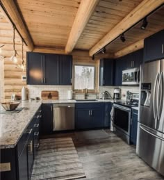 a kitchen with blue cabinets and stainless steel appliances in a log cabin style home on the shores of lake michigan