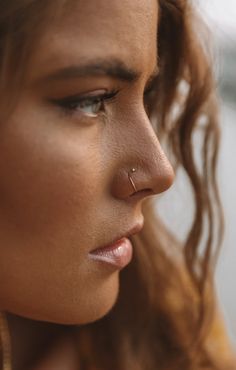 a close up of a woman with ear piercings on her nose looking off to the side