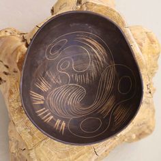 a wooden bowl sitting on top of a piece of driftwood next to a wall