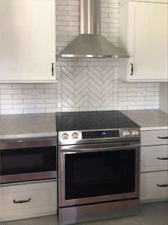 a stove top oven sitting inside of a kitchen next to white cupboards and drawers