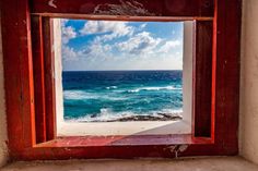 an open window overlooking the ocean with blue sky and white clouds in the background,