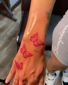 a woman's hand with pink butterflies on her left wrist and the word love written in red ink