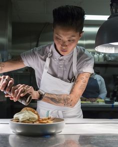 a man in an apron preparing food on top of a white plate next to a lamp