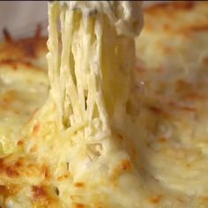 a piece of cheese being lifted from a casserole dish