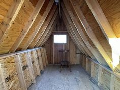 an attic with wooden walls and flooring that is being built into the side of it