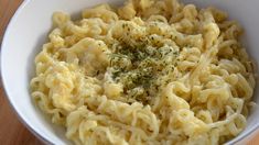 a white bowl filled with macaroni and cheese on top of a wooden table