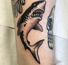 a man's leg with a shark and skull tattoo on the side of his leg