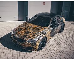 a car parked in front of a garage next to a brick floored driveway with an artistic design on it