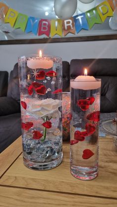 two vases with flowers and candles on a table