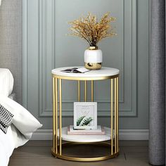 a white and gold side table with a plant on it next to a gray wall